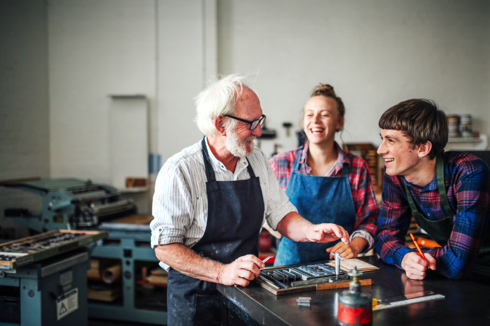 Best-Ager craftsman laughing with younger colleagues